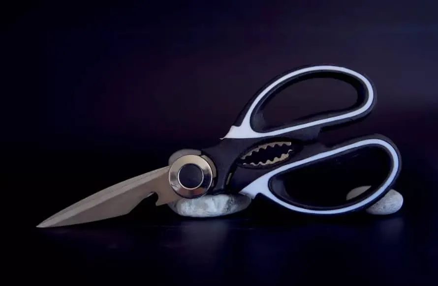 Para que serve a parte metálica entre as hastes da tesoura?