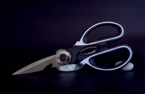 Para que serve a parte metálica entre as hastes da tesoura? 