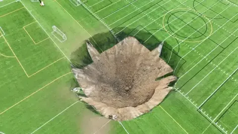 Vídeo aterrorizante mostra buraco de 30 metros engolindo um campo de futebol em segundos